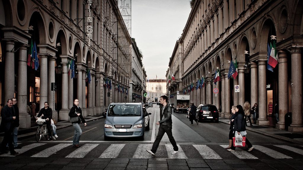 Pedoni sulle strisce pedonali di via Roma, a Torino, tra i portici