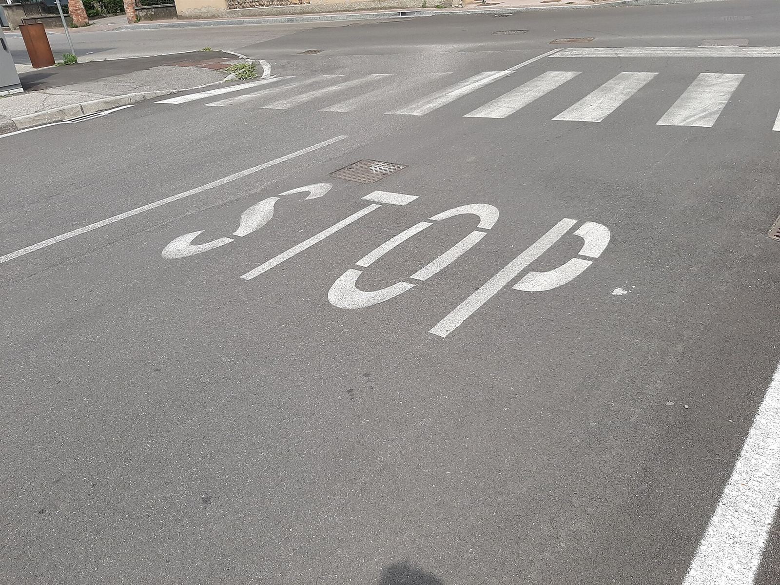 Scritta STOP e strisce pedonali appena ridipinte su una strada comunale